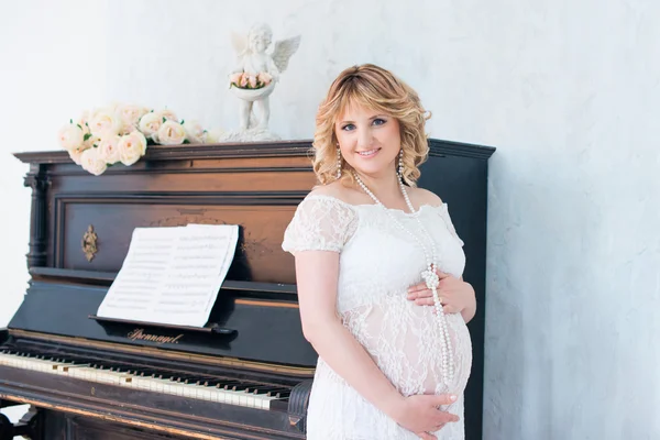 Gravid kvinna nära piano. musik för barn. — Stockfoto