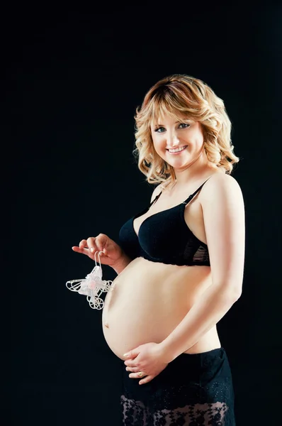 Pregnant woman in black lingerie smiling and gently hugs the tummy — Stock Photo, Image