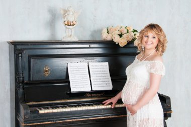 hamile sarışın kız piyano çalıyor.