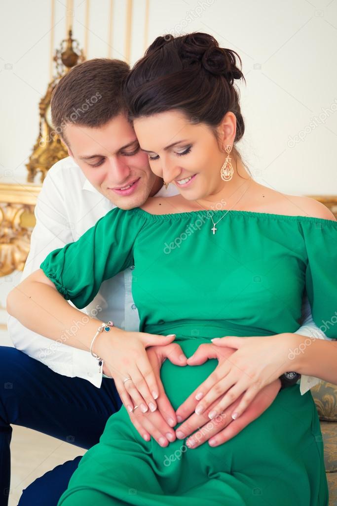 Beautiful pair of parents in anticipation of the child. Heart on pregnant tummy