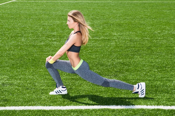 Snella ragazza atletica facendo esercizi mattutini allo stadio — Foto Stock