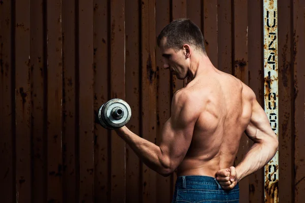 Young athletic man doing workout with heavy dumbbell — Stock Photo, Image