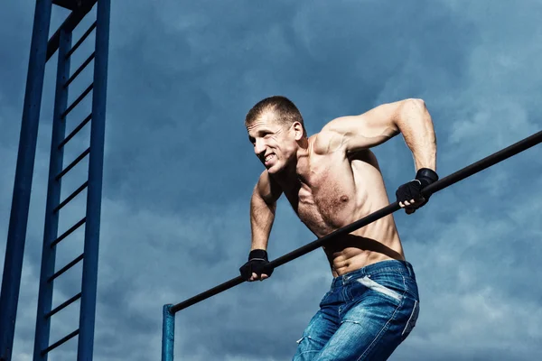 Atleet doen pull-up op horizontale balk. Mans fitness in het stadion — Stockfoto