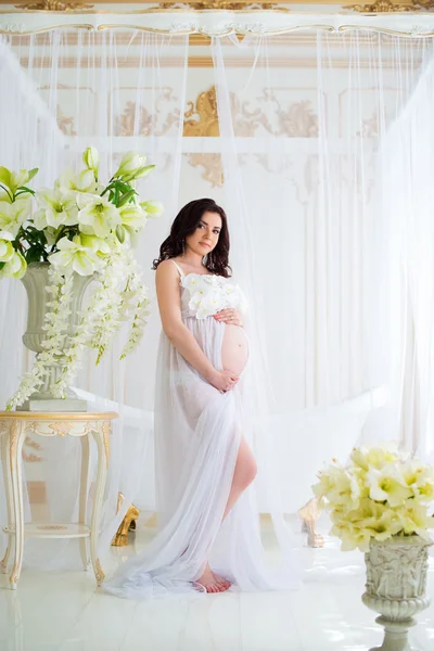 Menina grávida bonita no interior com flores e cortinas de tule — Fotografia de Stock