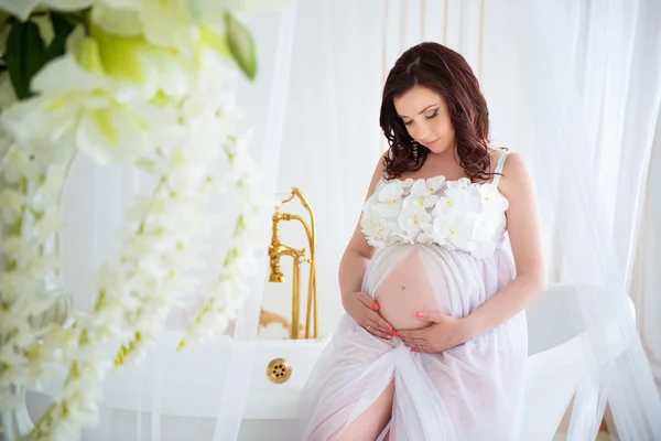 Nahaufnahme eines schwangeren Mädchens in einem wunderschönen Interieur mit Blumen — Stockfoto