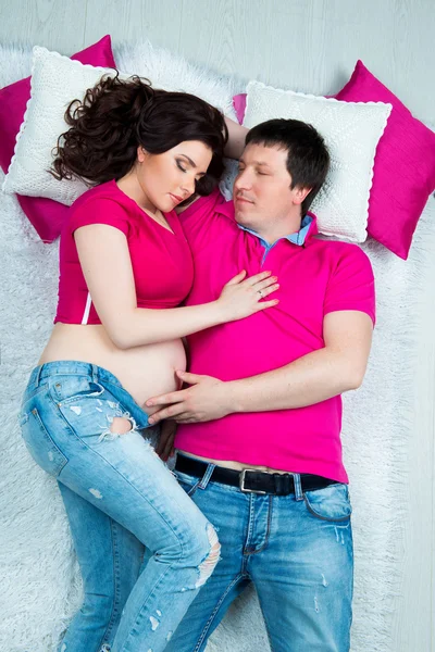 Beau jeune couple enceinte couché sur la literie lumineuse — Photo