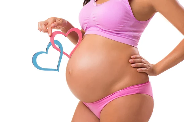 Nahaufnahme eines schwangeren Bauches mit rosa und blauen Herzen. Das Geschlecht des Babys erraten: Mädchen, Junge oder Zwillinge. — Stockfoto