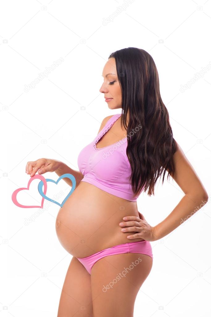 Pregnancy, maternity. Who is born: girl, boy or twins. Pregnant mother holding pink and blue hearts at the belly.