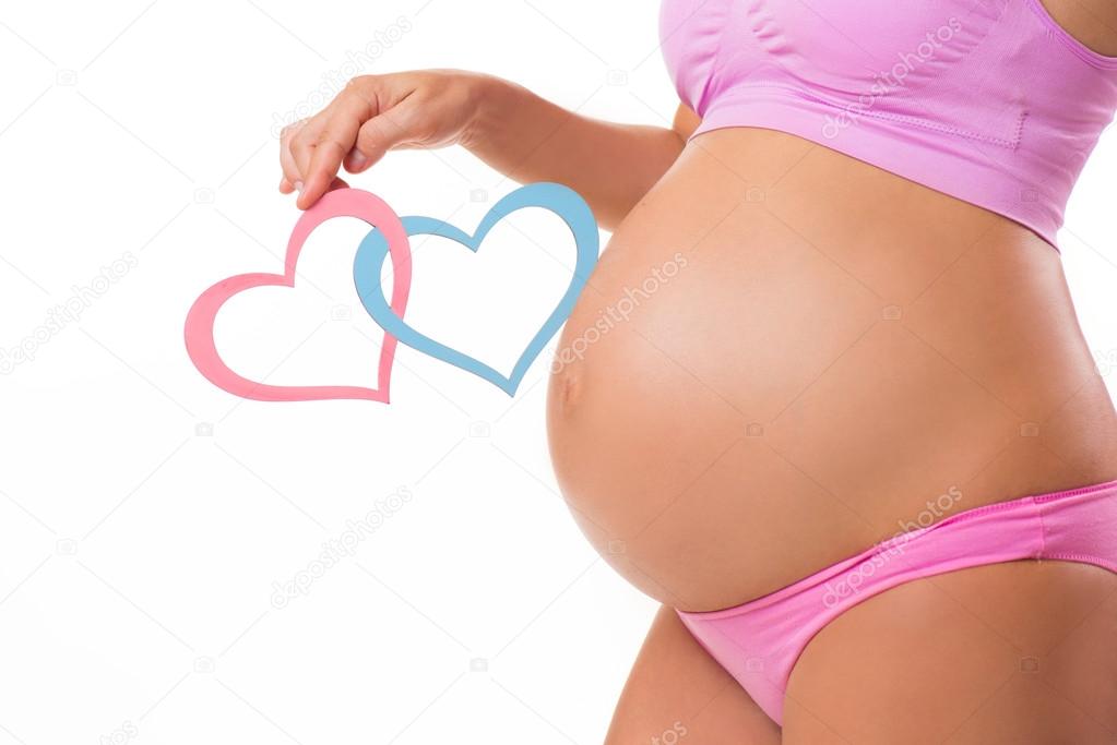 Close-up of a pregnant belly with pink and blue hearts. Guess the sex of the baby-child: girl, boy or twins.