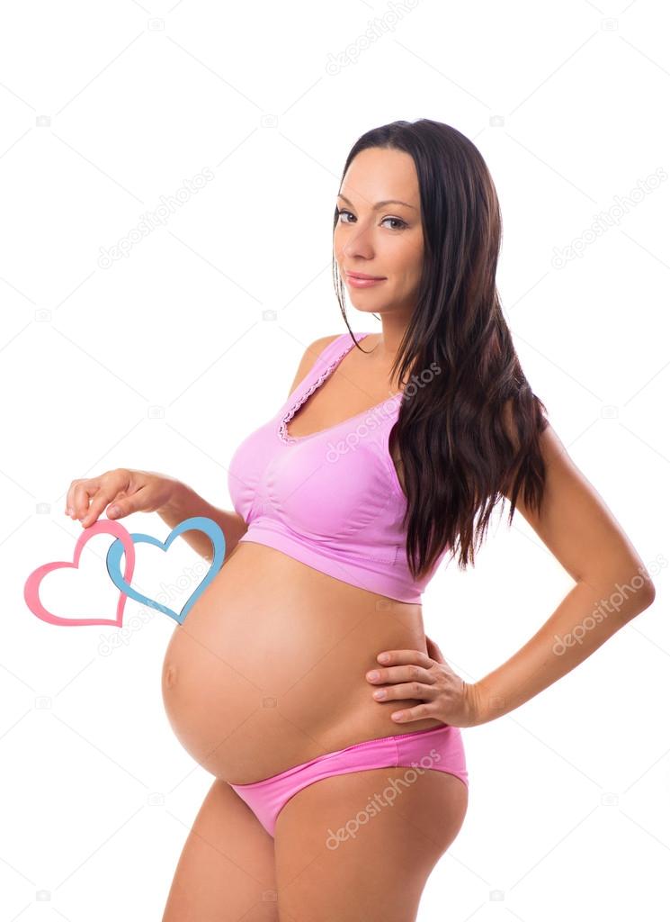 Pregnancy, maternity. Who is born: girl, boy or twins. Pregnant mother holding pink and blue hearts at the belly.
