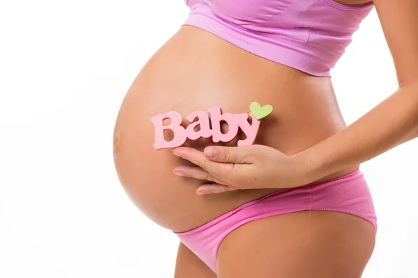 Kız bebek için pembe işaretiyle bir karın yatay close-up. Gebelikte bebeğin cinsiyetini belirlemek. — Stok fotoğraf