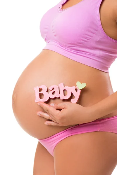 Close-up vertical de uma barriga grávida com sinal rosa para a menina. Determine o sexo do bebê durante a gravidez . — Fotografia de Stock