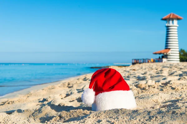 Boas festas de Ano Novo no mar. Chapéu de Papai Noel na praia de areia - conceito de férias de Natal — Fotografia de Stock