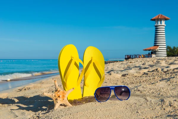 Viaje al mar. Soleadas vacaciones positivas en la playa. Sandalias amarillas, gafas de sol, estrellas de mar y faro — Foto de Stock