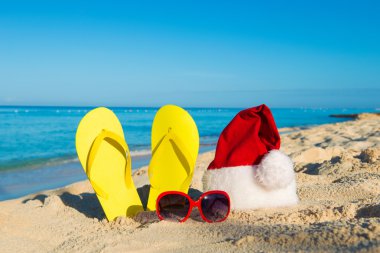 Christmas vacation at sea. Happy  New Year holidays. Santa hat, sandals, sunglasses on sandy beach