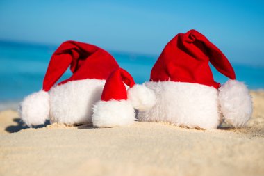 Santa hats on sandy beach  - concept of New Year family holiday with the children on the sea.
