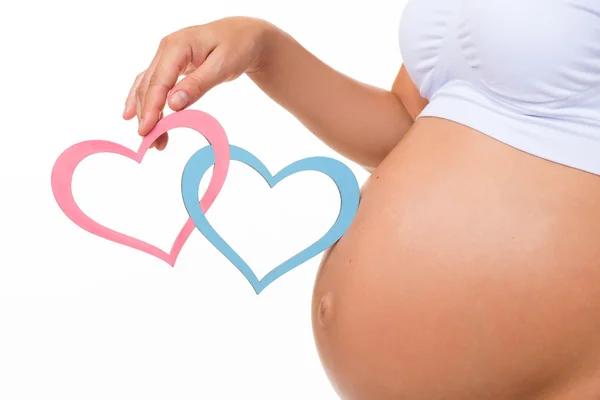 Schwangerschaftsbauch mit blauem und rosa Herz. horizontale Nahaufnahme. bestimmen das Geschlecht des Kindes: Zwillinge, Mädchen oder Junge. — Stockfoto