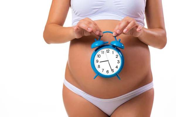 Счастливой беременности. Беременный живот с будильником. Концептуальный образ. Скоро роды. Развитие плода по месяцам — стоковое фото