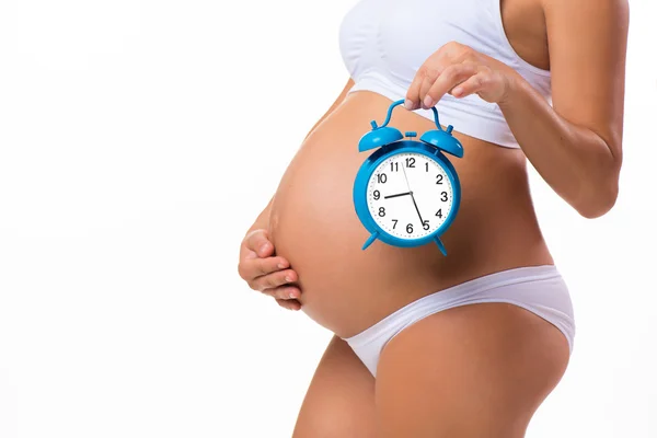 Happy pregnancy. Pregnant belly with alarm clock. Conceptual image. Soon birth. Fetal development by months Stock Image