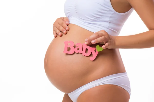怀孕肚为女婴粉红色题词。怀孕的女人在等一个女儿。白色背景上孤立的特写水平. — 图库照片