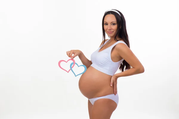 Vientre embarazada con corazón azul y rosa. Primeros planos horizontales. Determinar al niño: gemelos, niña o niño . — Foto de Stock