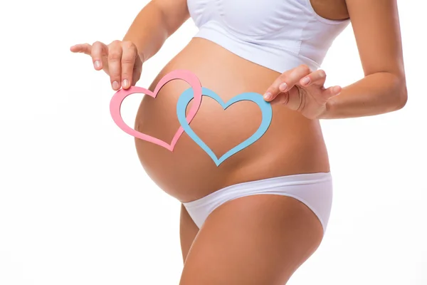 Pregnant belly with blue and pink heart. Horizontal closeup. Determine the child: twins, girl or boy. — Stockfoto