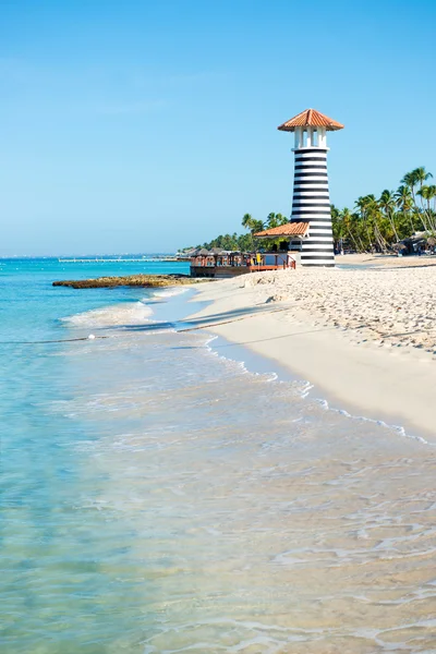 Mooie dag op zee. Witte zand, tropische palmbomen en vuurtoren op zanderige kust — Stockfoto