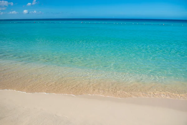 Azuurblauwe turquoise kalme zee, heldere blauwe hemel, zandstrand en platte horizon — Stockfoto