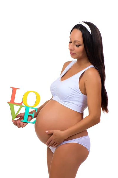 Метка Любовь в руках беременной женщины изолированы на вертикальном белом фоне — стоковое фото