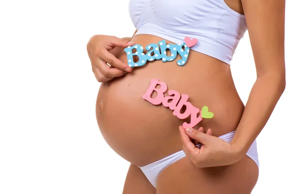 Primer plano de la barriga embarazada con etiquetas azules y rosadas "Bebé" para recién nacidos, niños o gemelos . — Foto de Stock