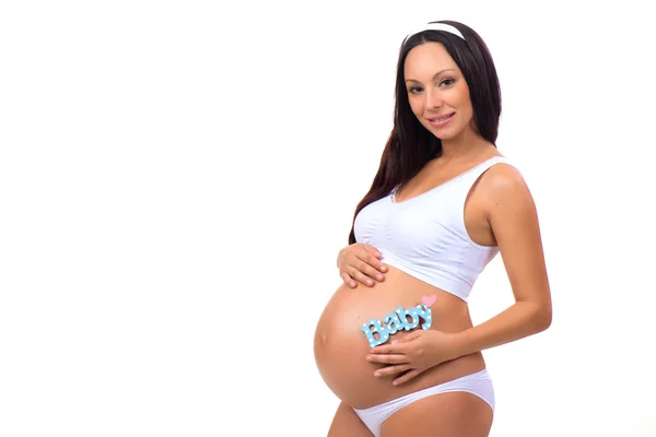 Ευτυχή εγκυμοσύνη. Χαμογελώντας έγκυος γυναίκα που κρατά κοντά κοιλιά μπλε ετικέτα μωρού για νεογέννητο αγόρι — Φωτογραφία Αρχείου