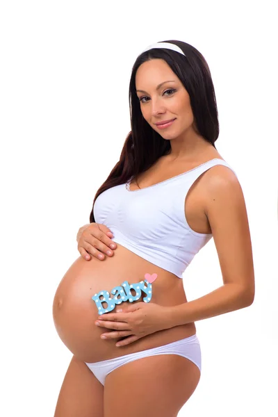 Ευτυχή εγκυμοσύνη. Χαμογελώντας έγκυος γυναίκα που κρατά κοντά κοιλιά μπλε ετικέτα μωρού για νεογέννητο αγόρι — Φωτογραφία Αρχείου