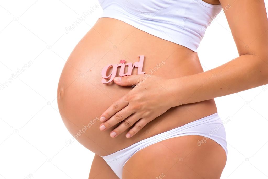 Close-up of pregnant tummy with pink label Girl for newborn daughter on  horizontal white background