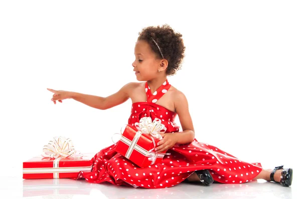 Curly girl in a red polka-dot dress parses New Year holiday gifts — 스톡 사진