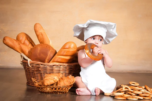 Маленький кухар з багелем в руках . — стокове фото