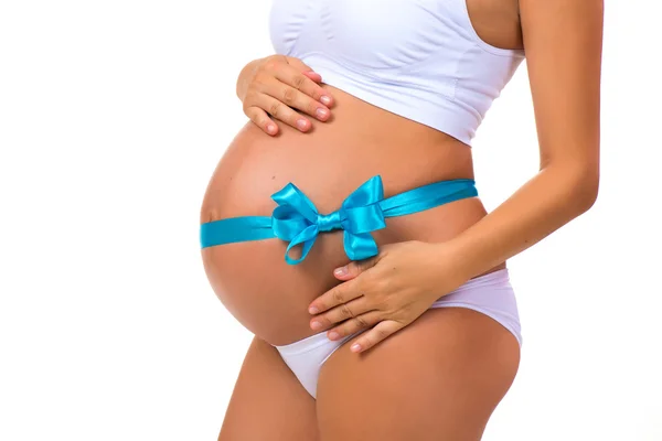 孕妇的肚子，带着弓和蓝丝带的特写镜头。怀孕的概念。初生男婴. — 图库照片