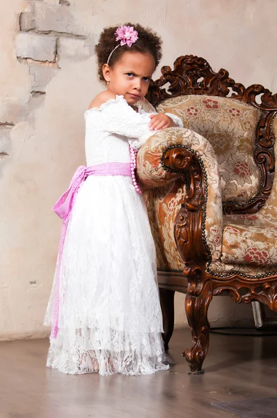 Chica africana sonriente con el pelo rizado en un vestido de encaje blanco en la silla vintage —  Fotos de Stock