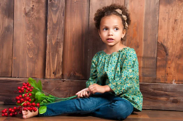 Niña africana en camisa rural con racimo de bayas. Fondo de pared de madera marrón —  Fotos de Stock