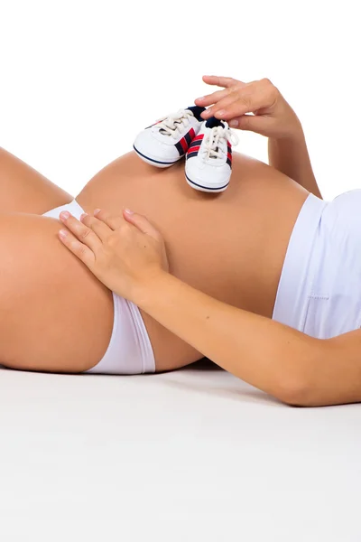 Kleine Schuhe für Neugeborene. Schwangerer Bauch aus nächster Nähe. Babystiefel — Stockfoto