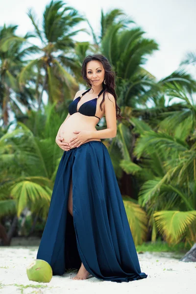 Junge schwangere Frau umarmt Bauch. Exotische Natur, Palme. Glückliche Mutterschaft — Stockfoto