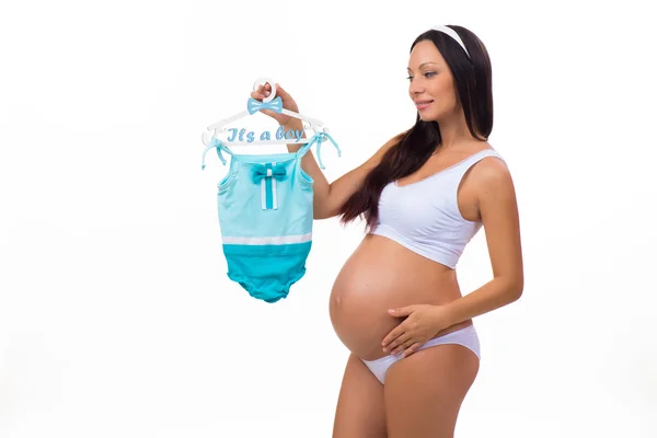 Mujer embarazada feliz con ropa de bebé para el niño recién nacido. Género de un niño — Foto de Stock
