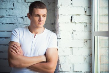 Pencere ve beyaz duvara yakın duran genç çekici adam