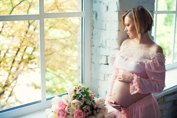 Chica embarazada cerca de la ventana. Feliz embarazo saludable. Esperando al bebé —  Fotos de Stock