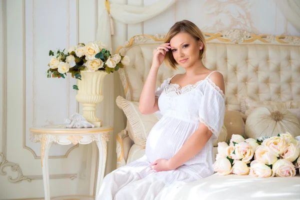 Zwangerschap en wachten voor baby. Zwangere moeder zittend op een bed van rozen — Stockfoto