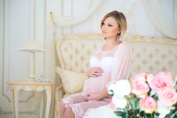 Embarazo y esperando al bebé. Madre embarazada sentada en una cama de rosas —  Fotos de Stock