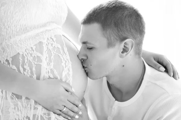 Una gravidanza sana e felice. Marito che abbraccia e bacia la pancia incinta di sua moglie, ritratto ravvicinato — Foto Stock