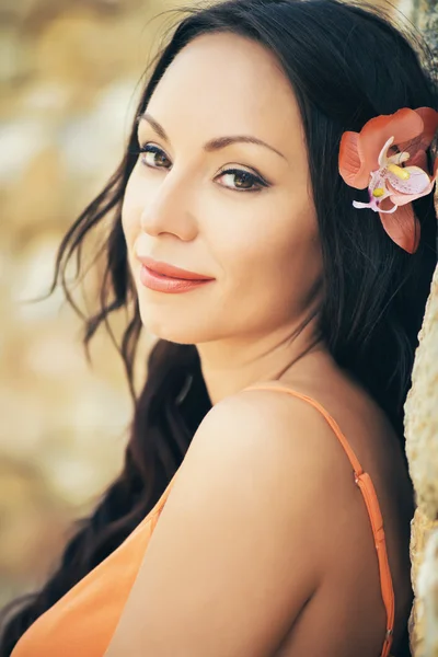 Bellissimo ritratto di una giovane donna bruna con un fiore d'arancio tra i capelli. Faccia sorridente — Foto Stock