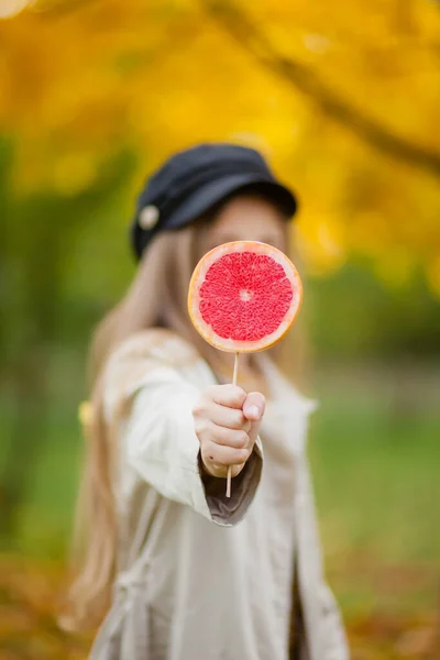 Blonde Girl Beige Trench Coat Black Cap Holds Grapefruit Stick — Stock Photo, Image