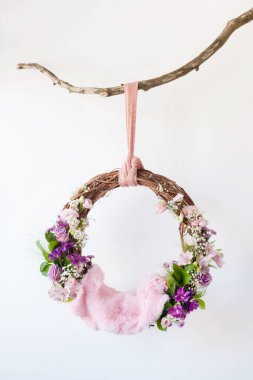 Yeni doğan bir bebeğin fotoğraf çekimi için beyaz arka planda beşikteki üzüm halkası ve pembe çiçekler.