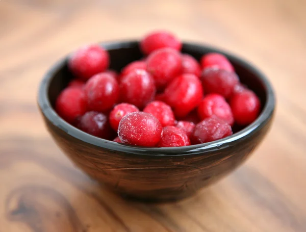 Cranberries in wooden bowl on wooden background — Stock Photo, Image